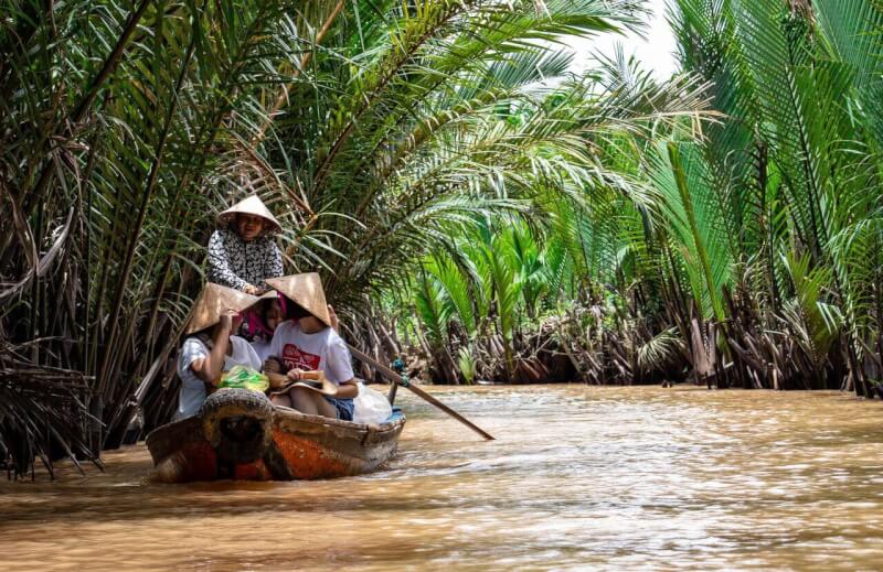 Một nhóm người trên một chiếc thuyền gỗ trôi dọc theo đồng bằng sông Cửu Long ở Việt Nam.